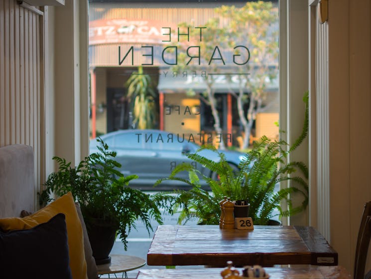 Cosy bench seating next to a window, with lots of fresh greenery / ferns