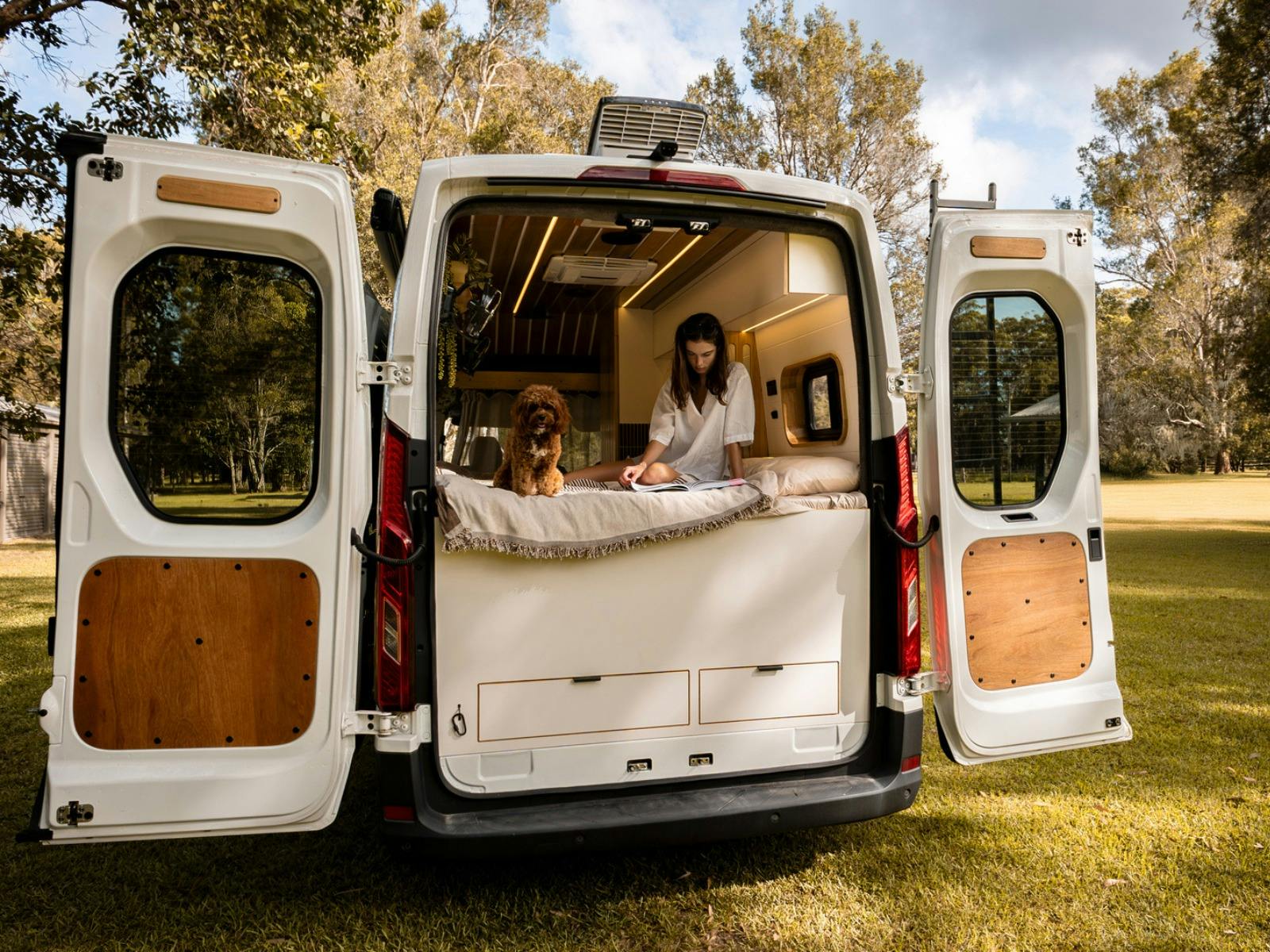 A woman and a dog sitting in the back of a motorhome