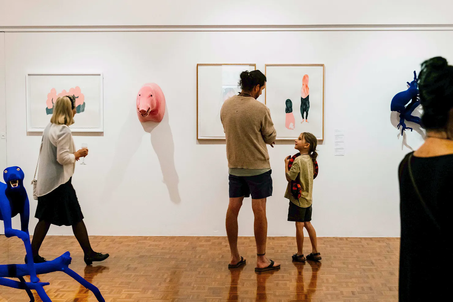 A father and daughter standing in front of quirky art on a gallery wall