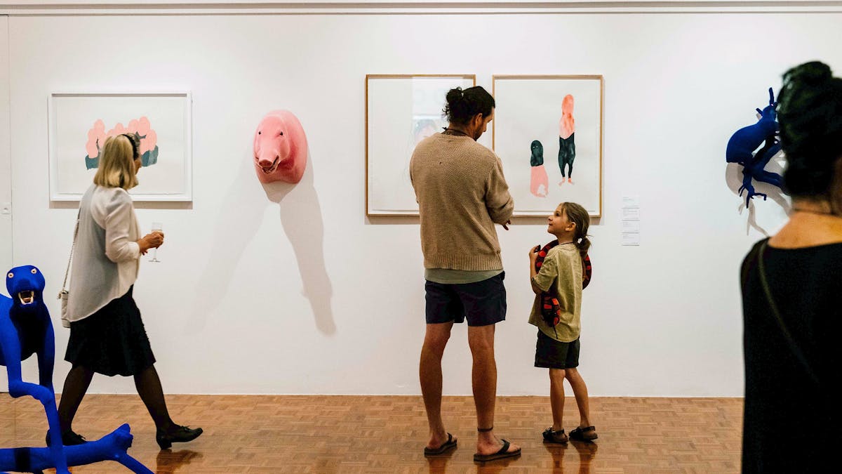 A father and daughter standing in front of quirky art on a gallery wall