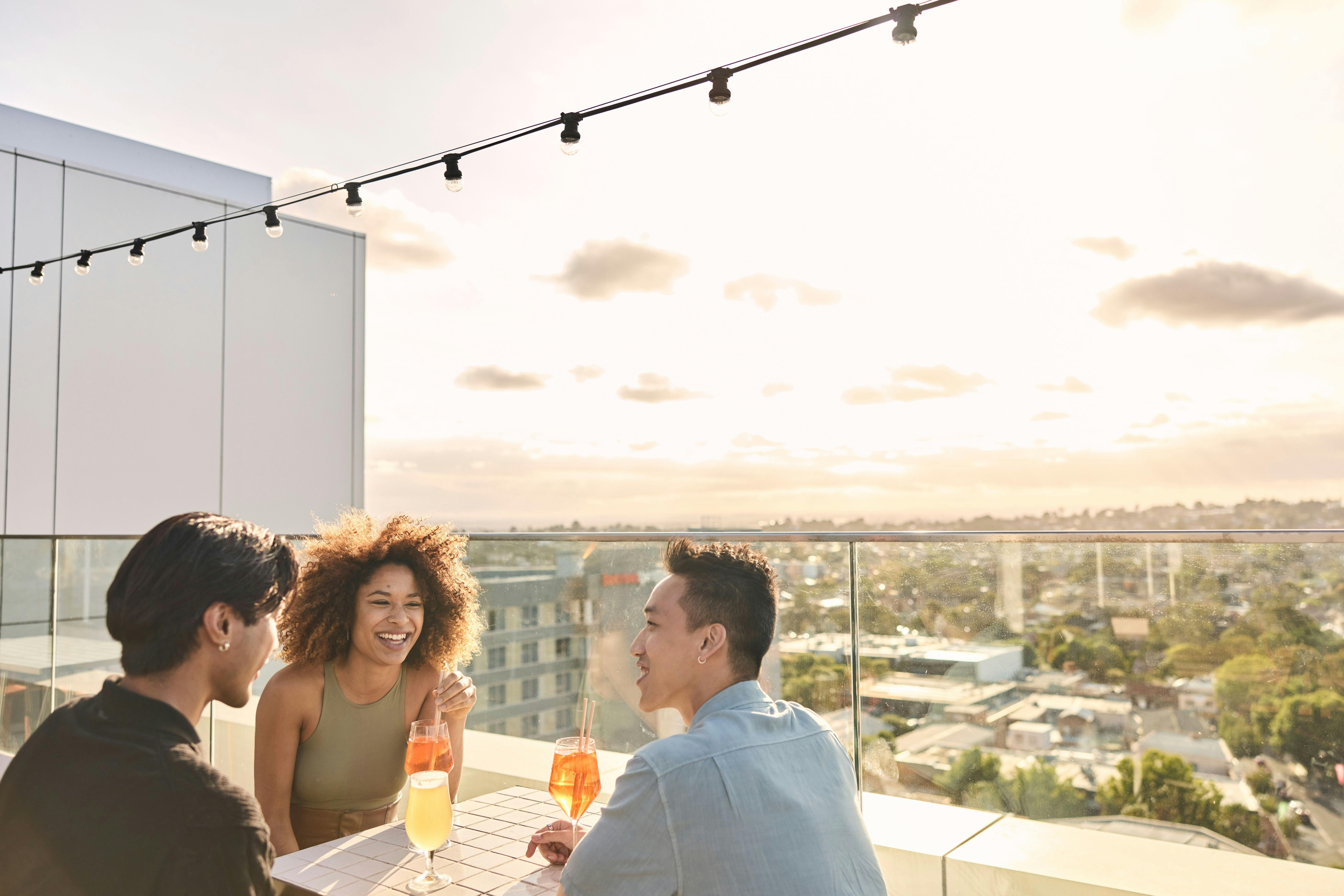 Three friends with drinks on balcony with view