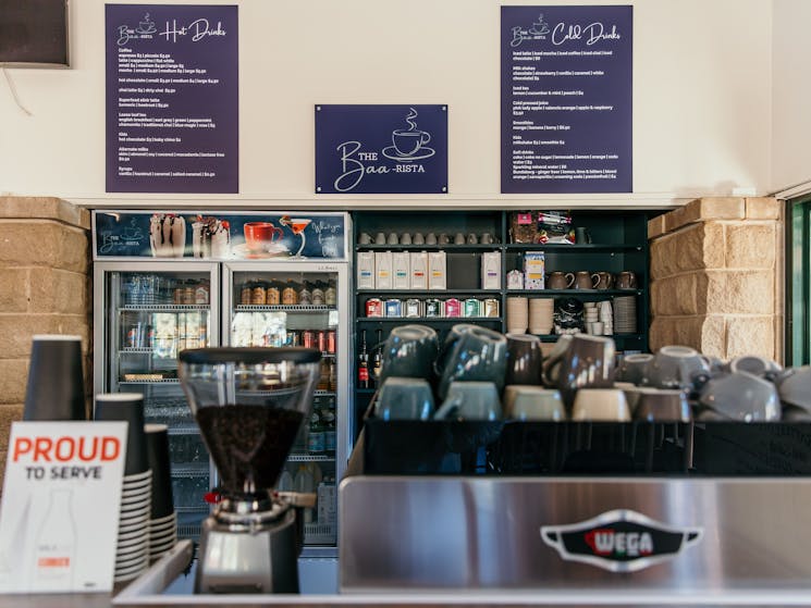 An espresso machine with coffee cups and coffee menus on the wall of a cafe.