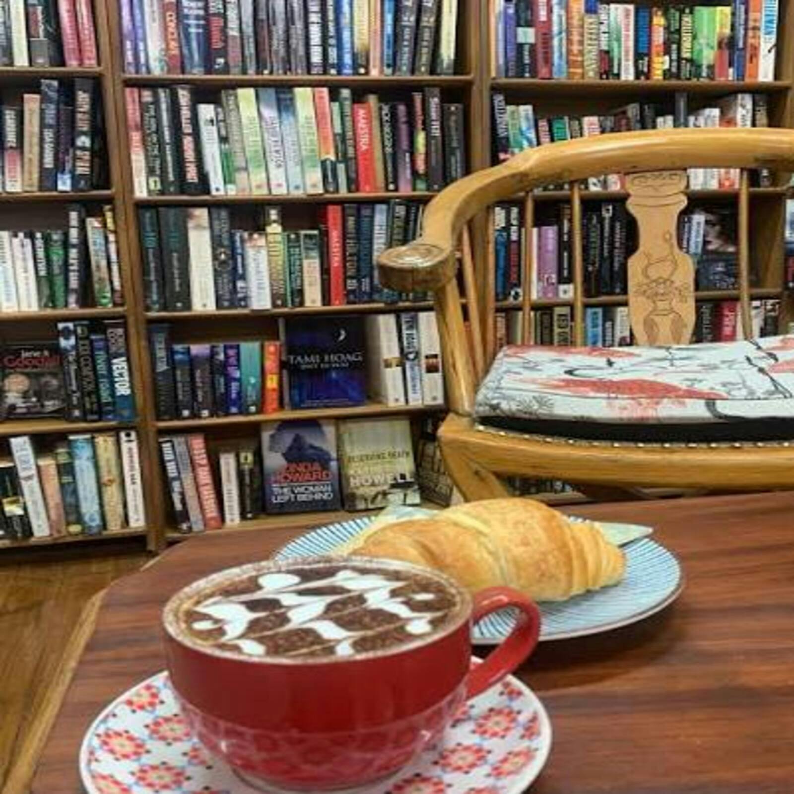 bookshelves in background, crossoint and coffee focus, chair and table