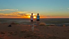 Children watching sunset on sandune.
