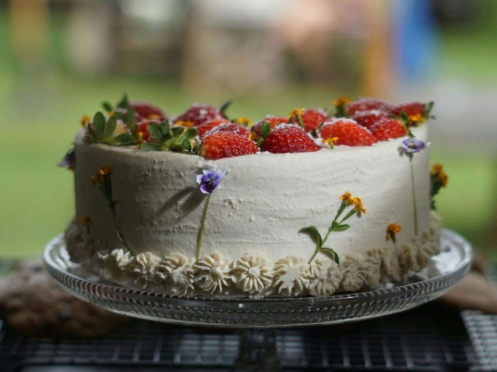 white cake decorated with strawberries and flowers