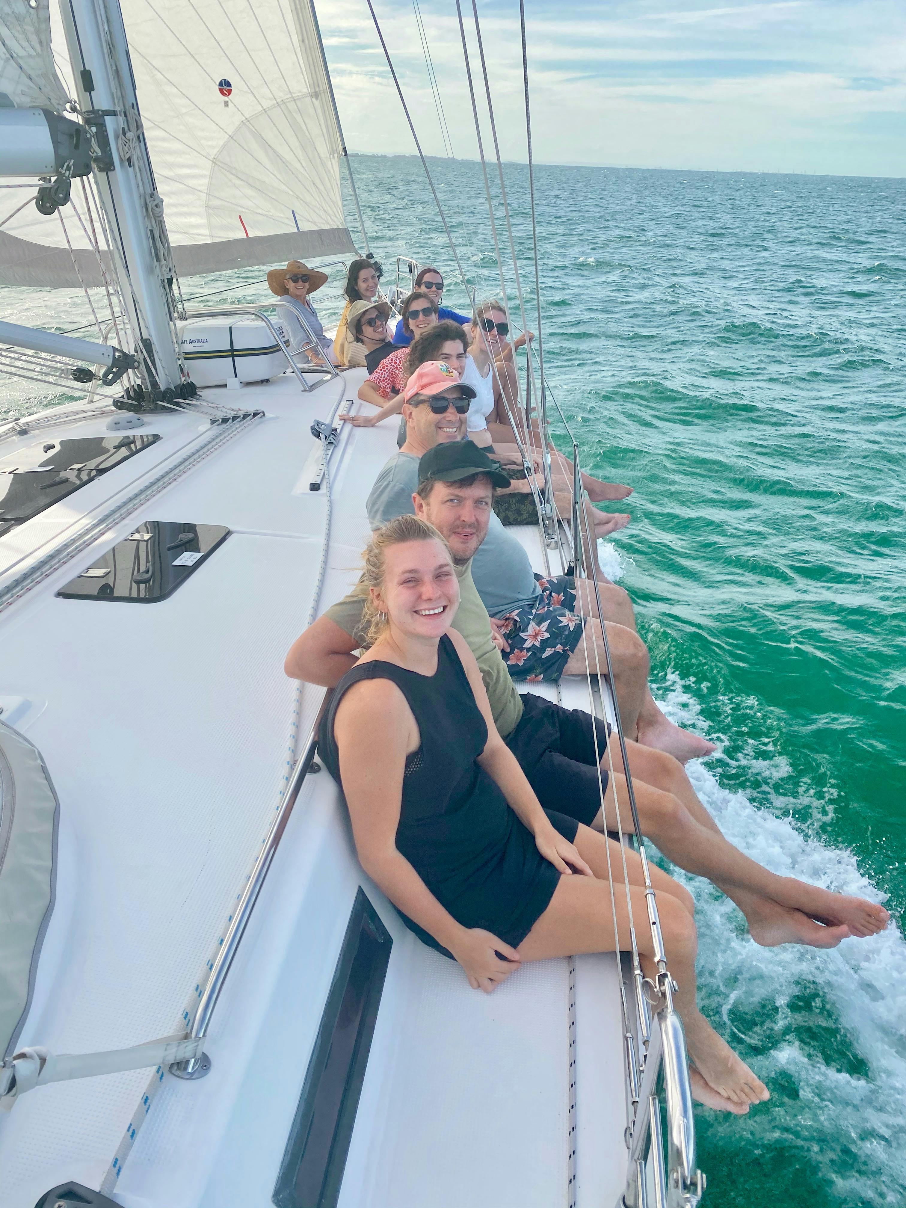 Guests enjoying sitting on the rail while sailing