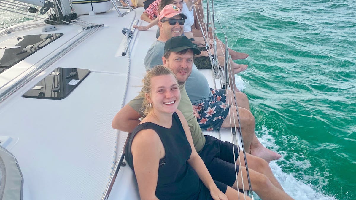Guests enjoying sitting on the rail while sailing