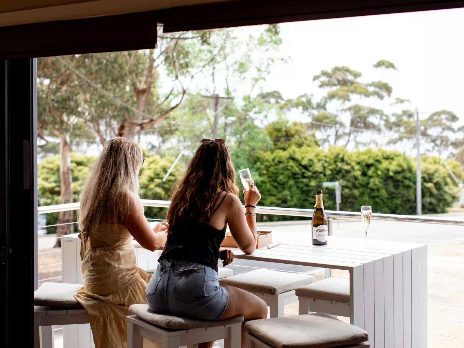 Two guests on the balcony at Binalong Bay Beach House, Tasmania.