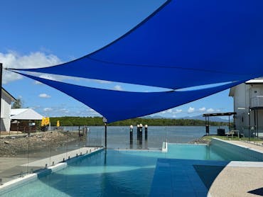Large pool with shade sails overlooking river Large pool with shade sails overlooking river