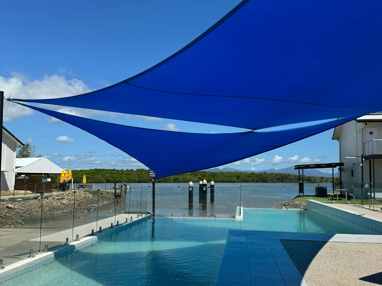 Large pool with shade sails overlooking river Large pool with shade sails overlooking river