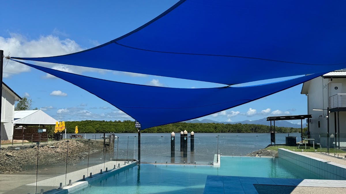 Large pool with shade sails overlooking river