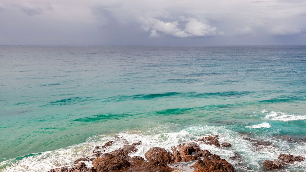 The calm ocean reflects the edge of the storm cloud atPoint Perry