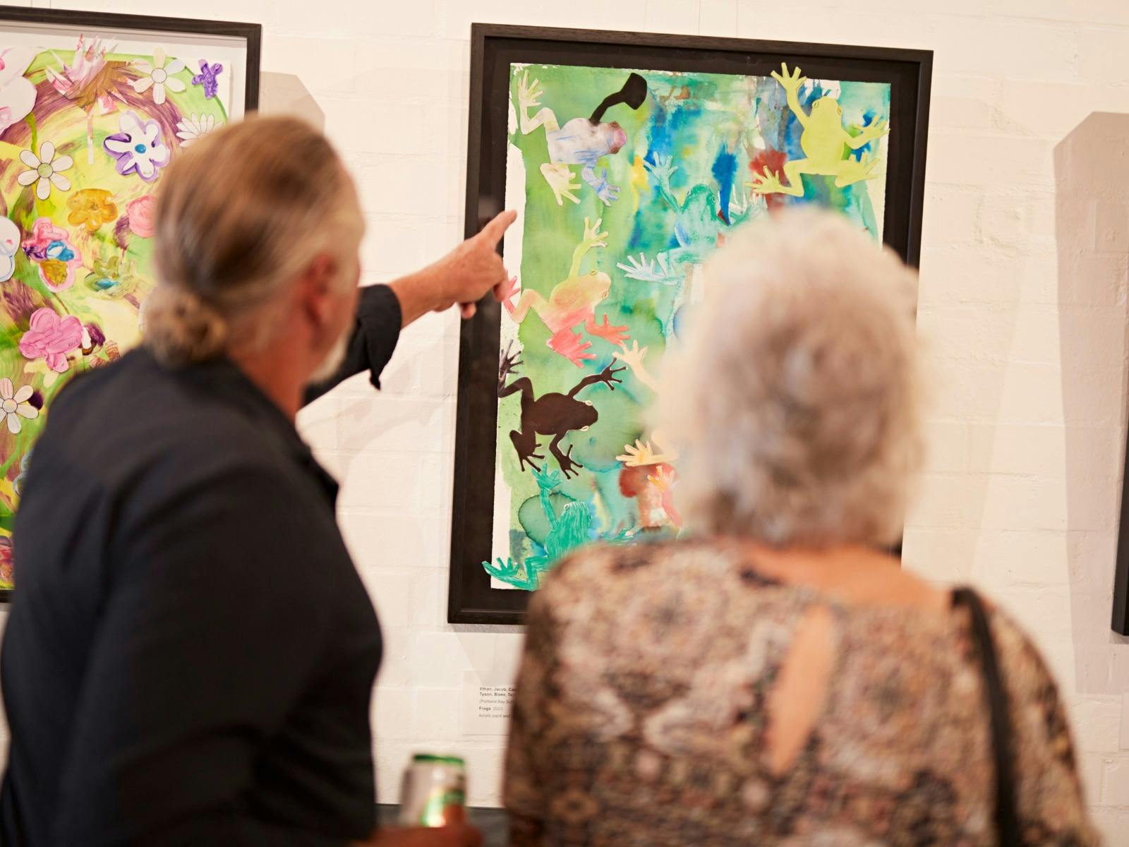 A man and a woman discussing paintings in the gallery.