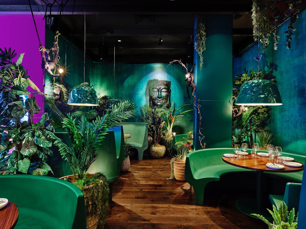 A view into the hidden jungle oasis at the back of PingPong featuring lush greenery & booth seating