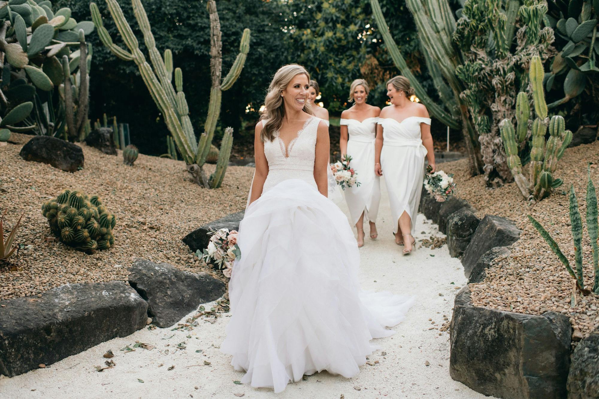 bride and bridesmaid walking through cactus garden