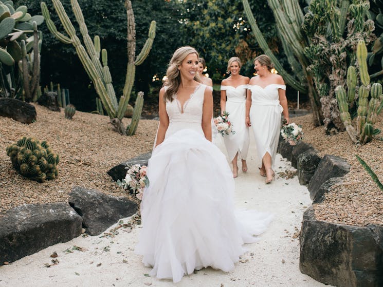 bride and bridesmaid walking through cactus garden