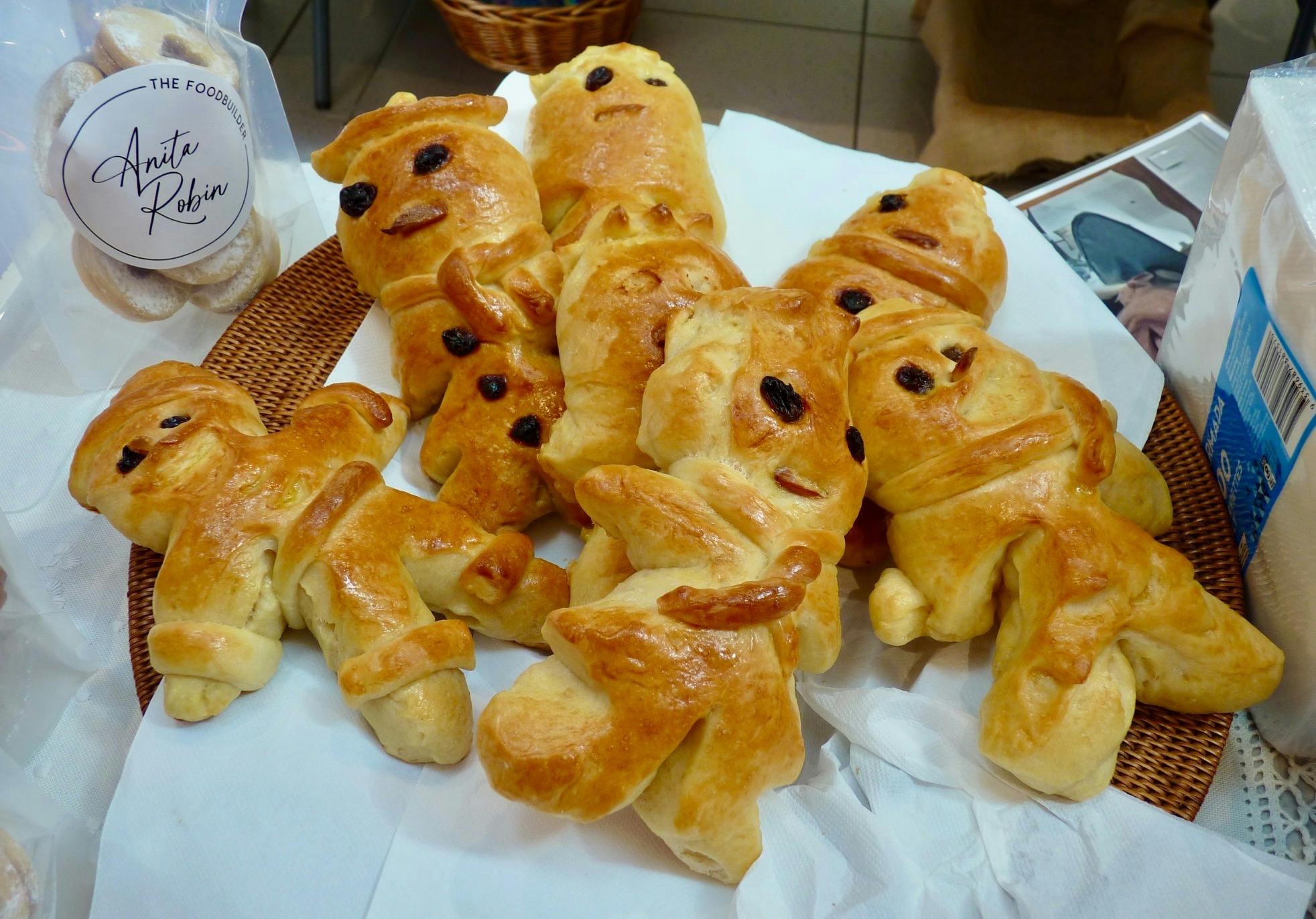 Golden-brown Swiss bread figures called Grittibänz, decorated with raisins and arranged in a lined b