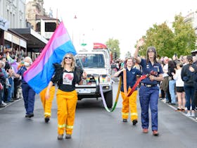 CFA volunteers fly bisexual flag and hold rainbow water hoses in front of fire truck