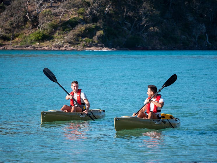 Two kayaks smiling and kayaking the pambula river