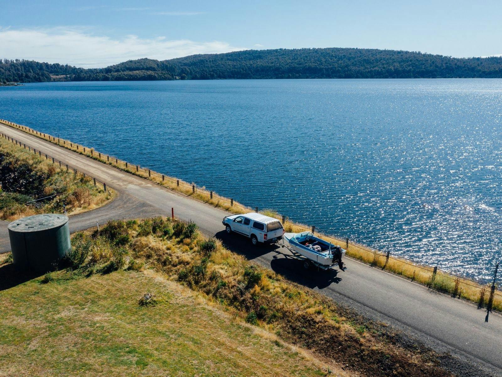 A car driving alongside Bradys Lake. The car is towing a boat.