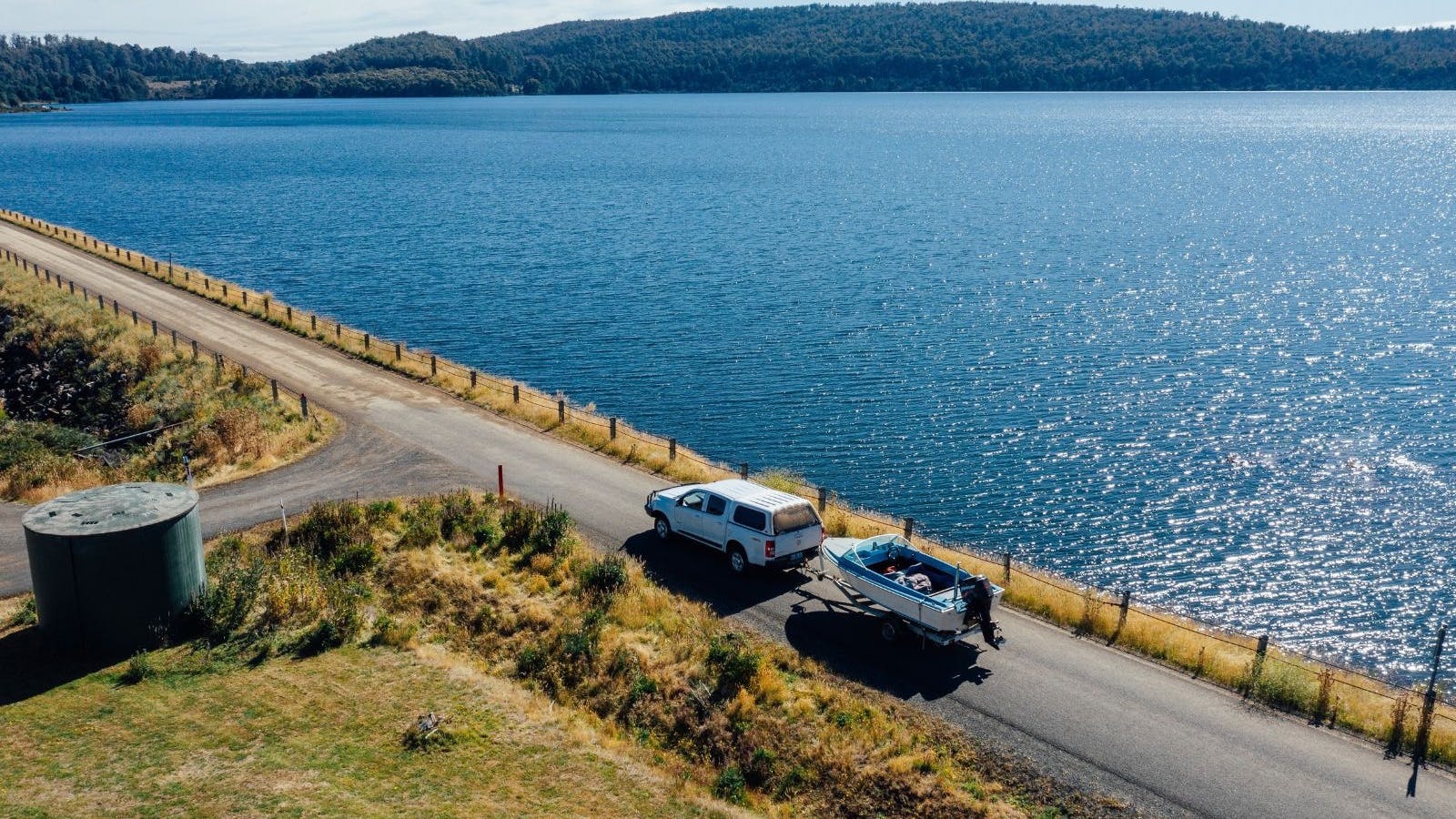 A car driving alongside Bradys Lake. The car is towing a boat.