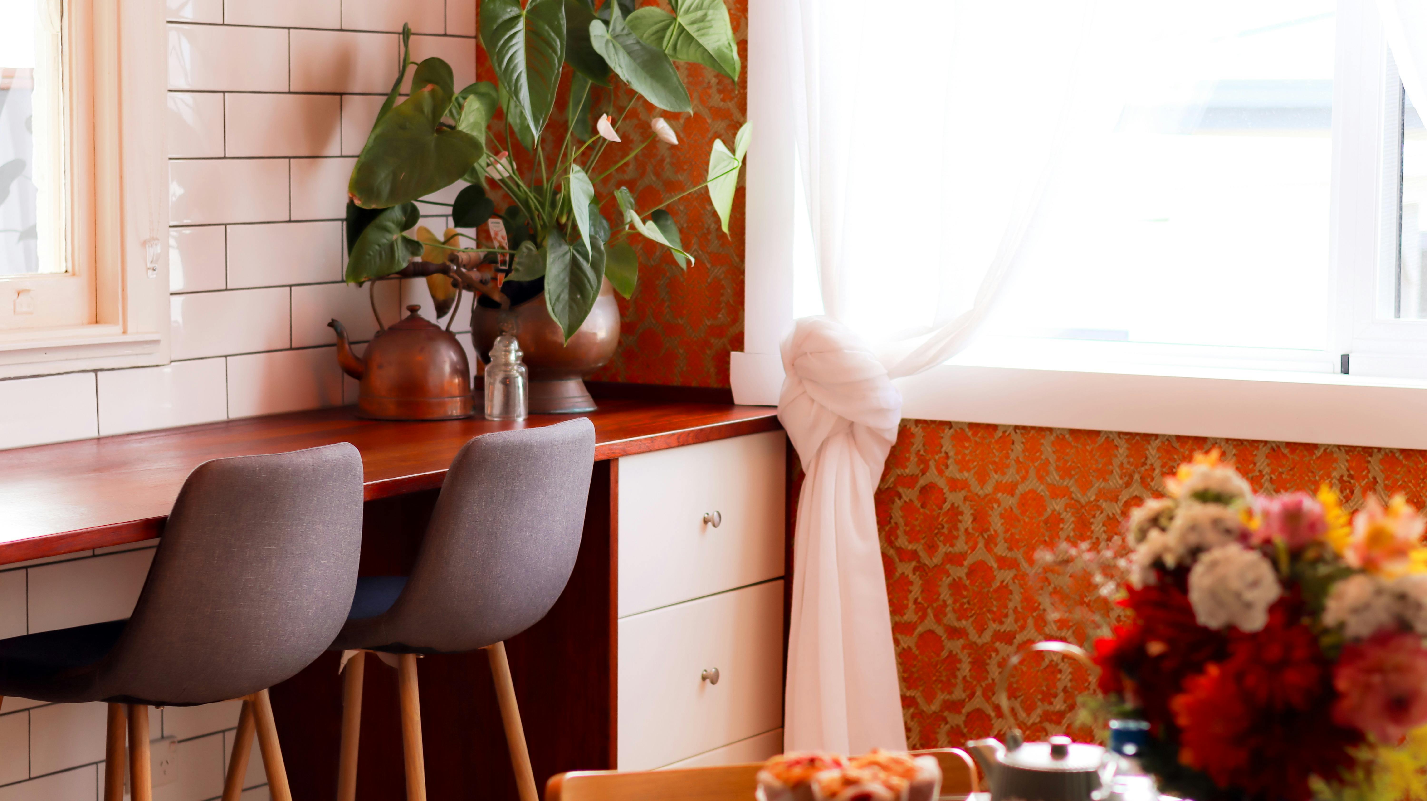Timber bench top with seating. Live plants and decor, naturally lit space.