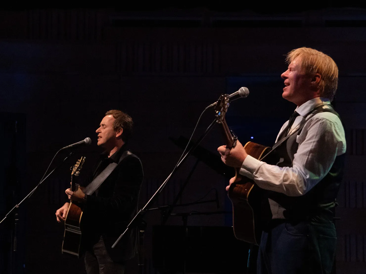 Two middle aged man playing guitar on the stage.