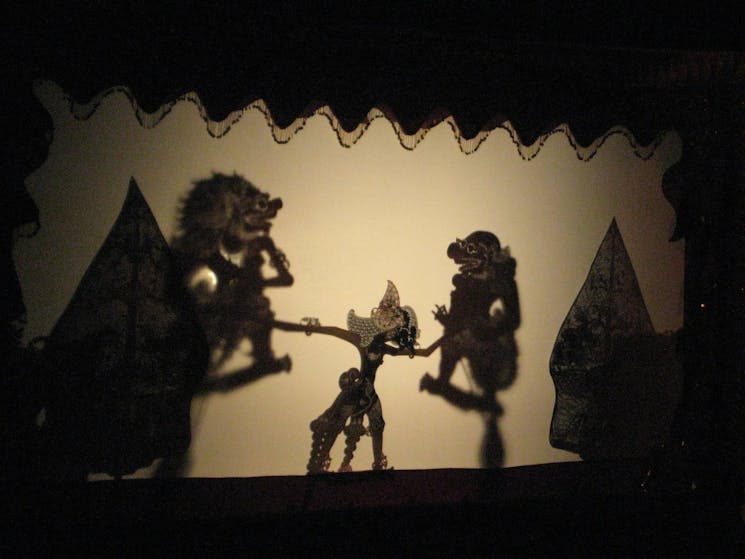 Javanese shadow puppets projected on a white wall