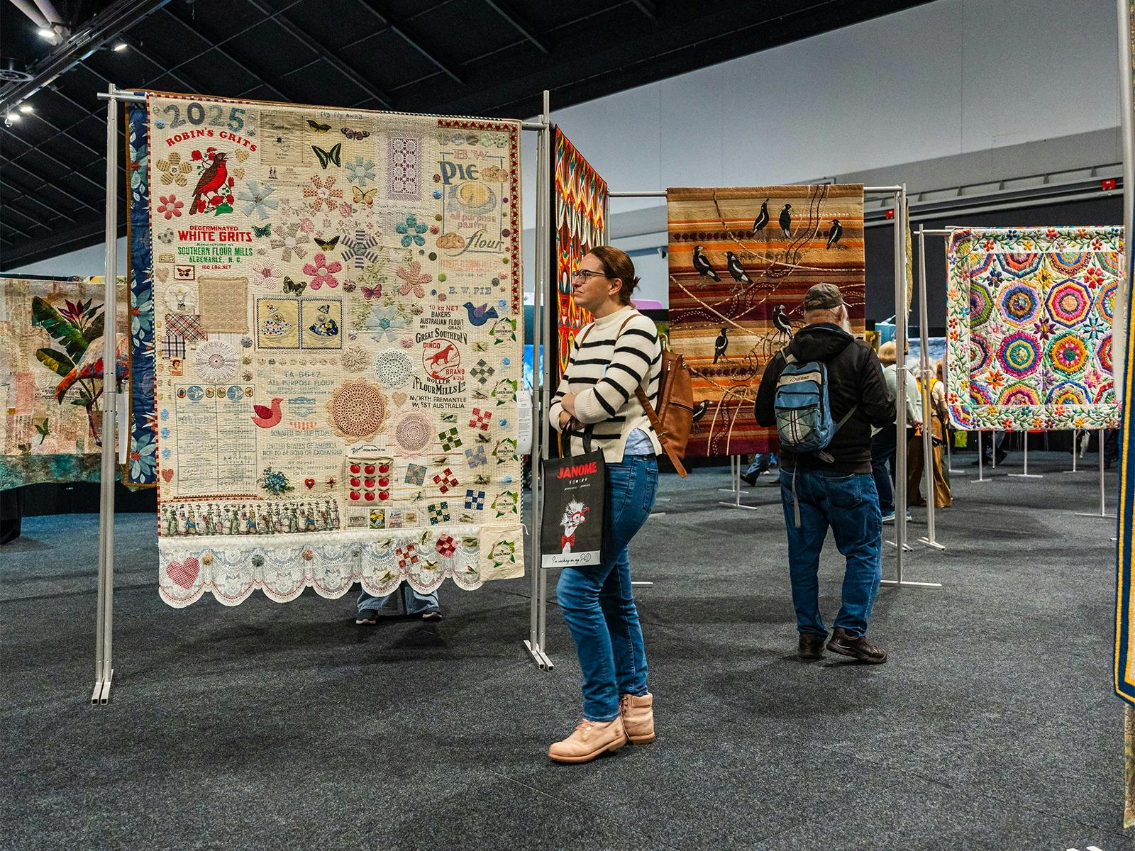 Quilt gallery Visitors admire colourful handmade quilts displayed in the exhibition gallery.
