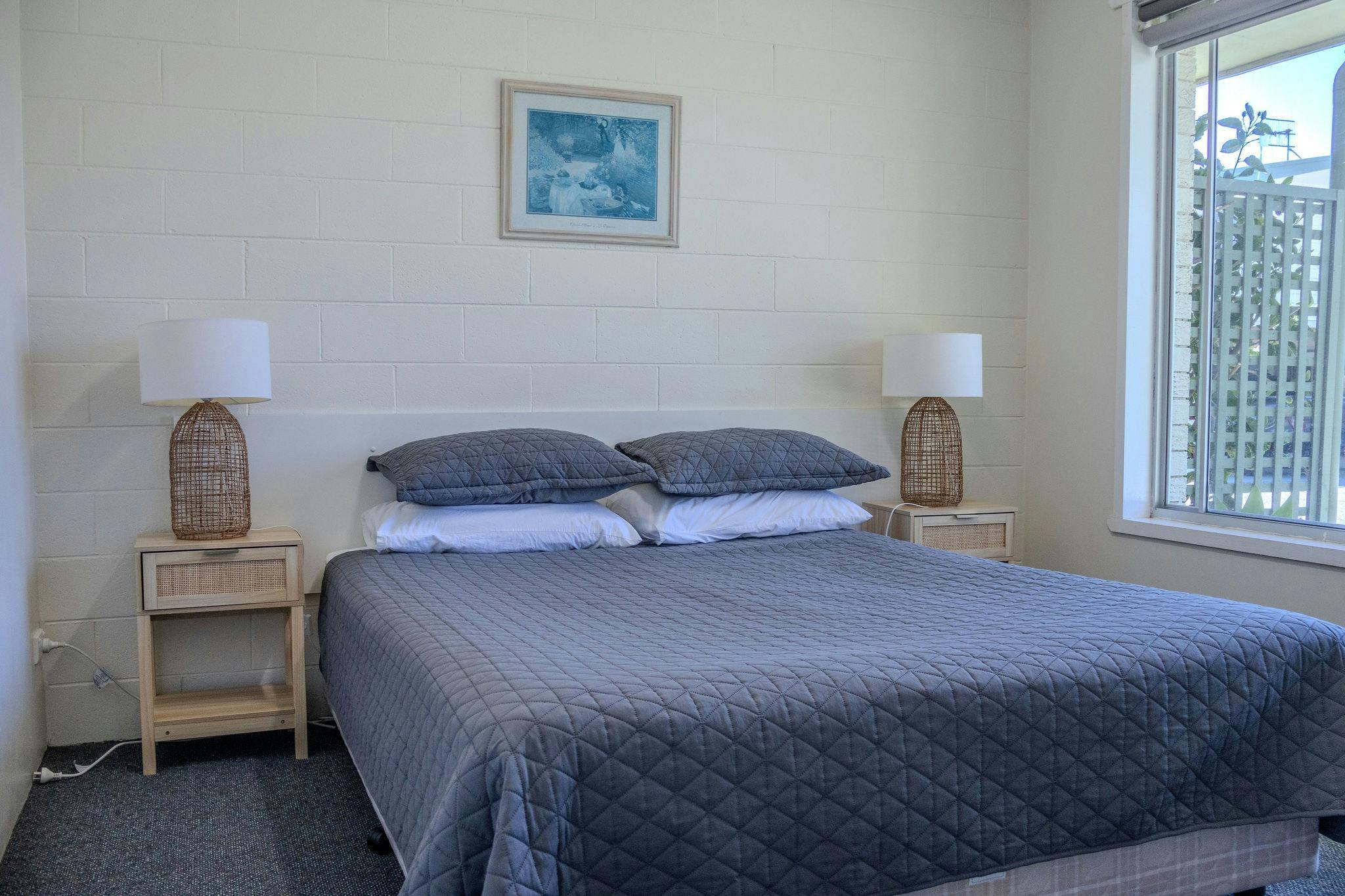Queen bedroom with bedside lamps in a Silver Bream Motel two-bedroom unit
