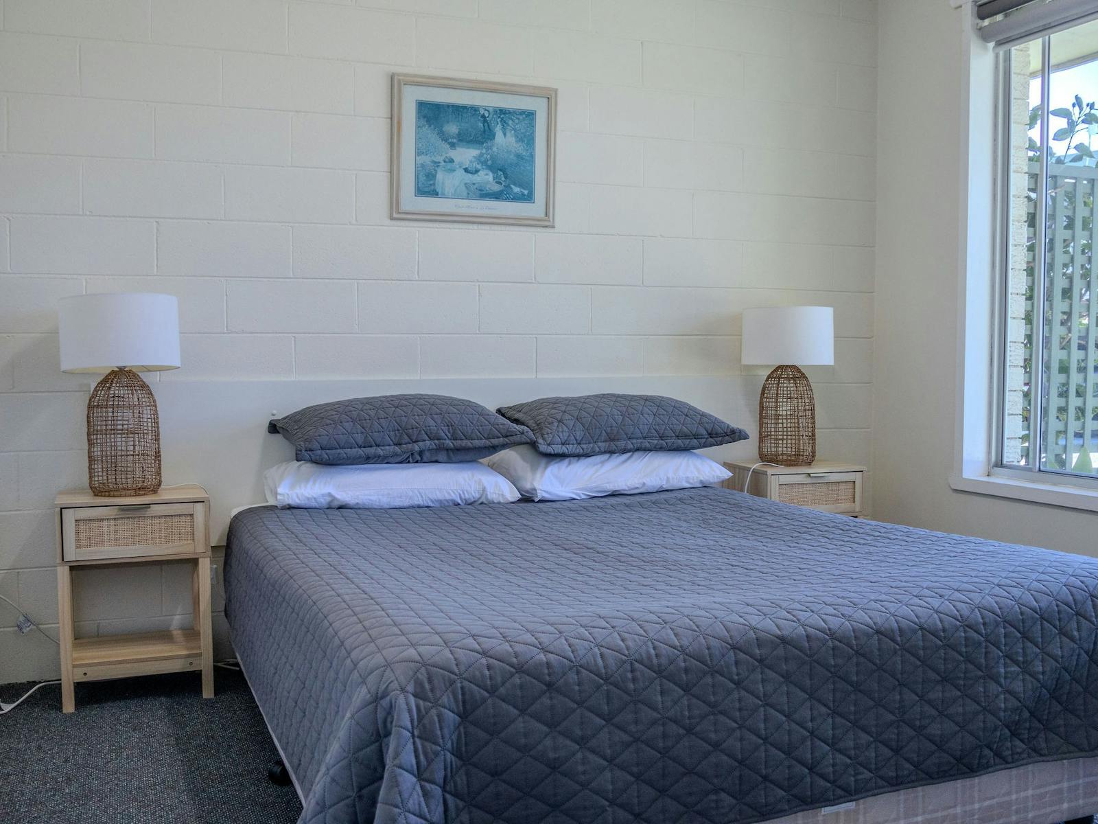 Queen bedroom with bedside lamps in a Silver Bream Motel two-bedroom unit