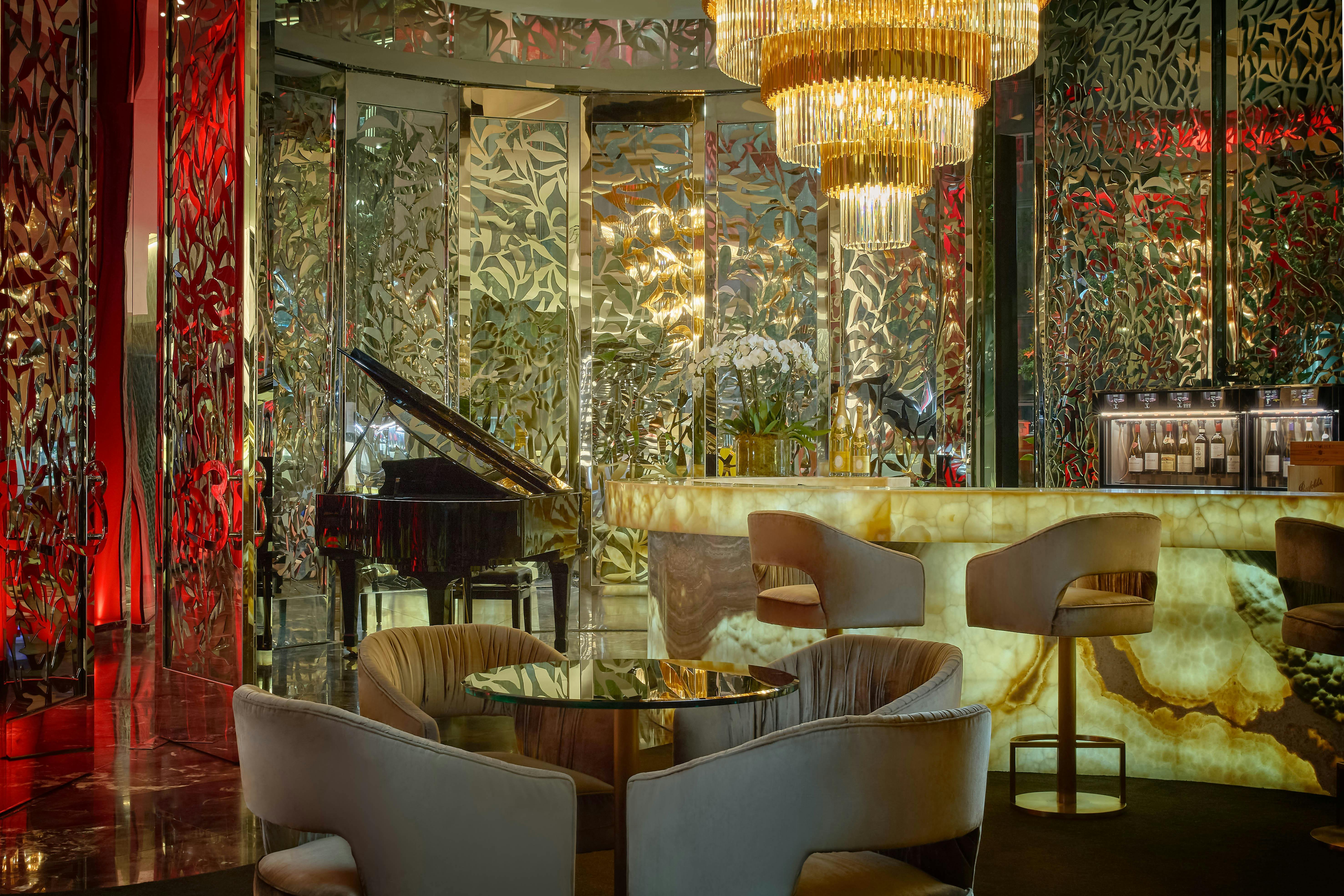 Moody interiors of bar seating, grand piano and chandelier in The Reserve Wine Bar