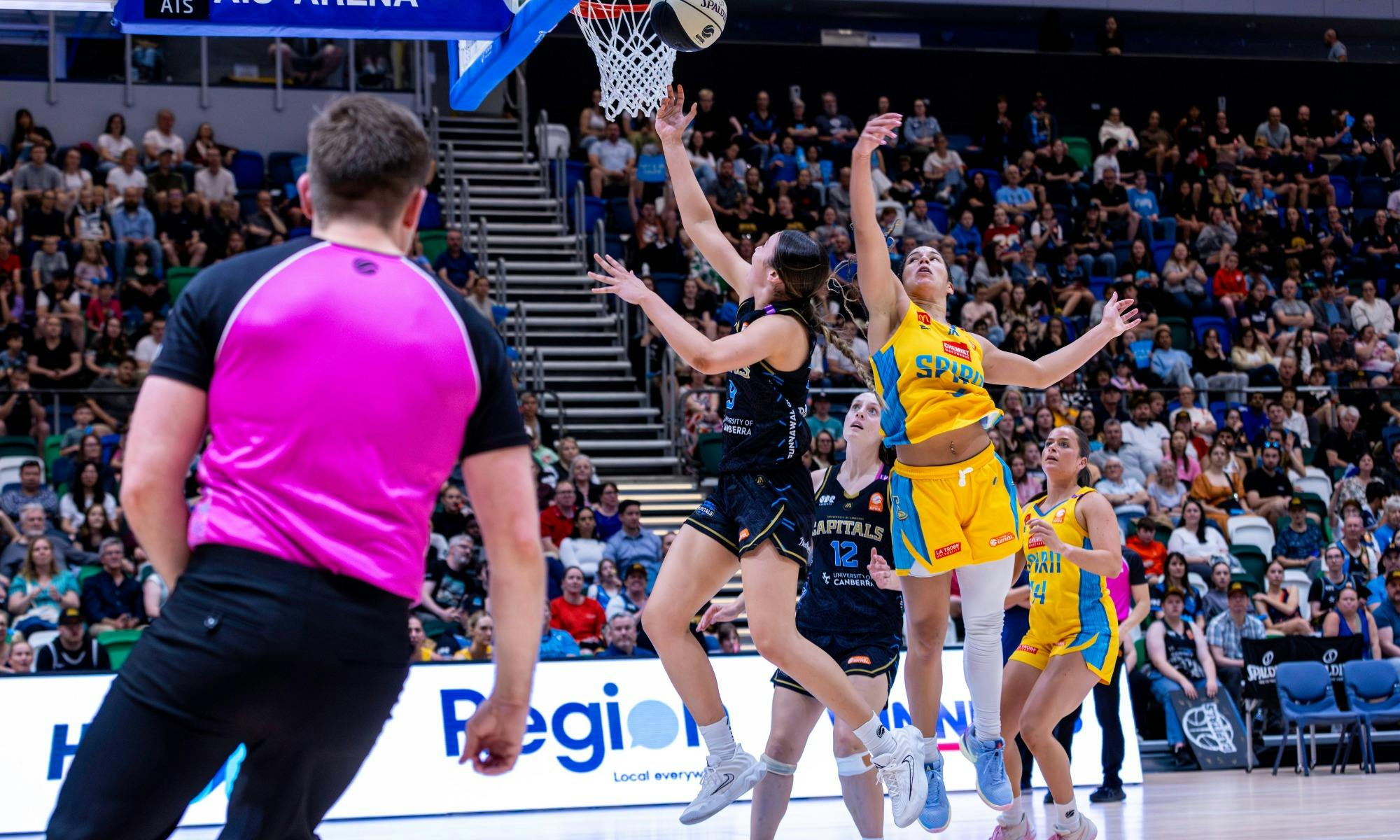 UC Capitals player driving to the basket for a layup during a WNBL game.