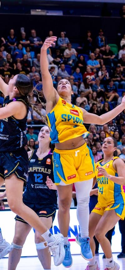 UC Capitals player driving to the basket for a layup during a WNBL game.