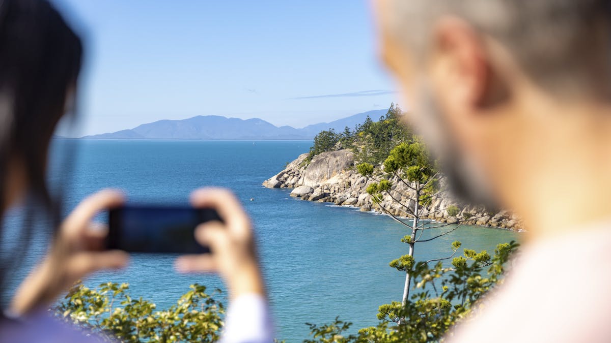 People taking iphone photo overlooking ocean and rocky headland