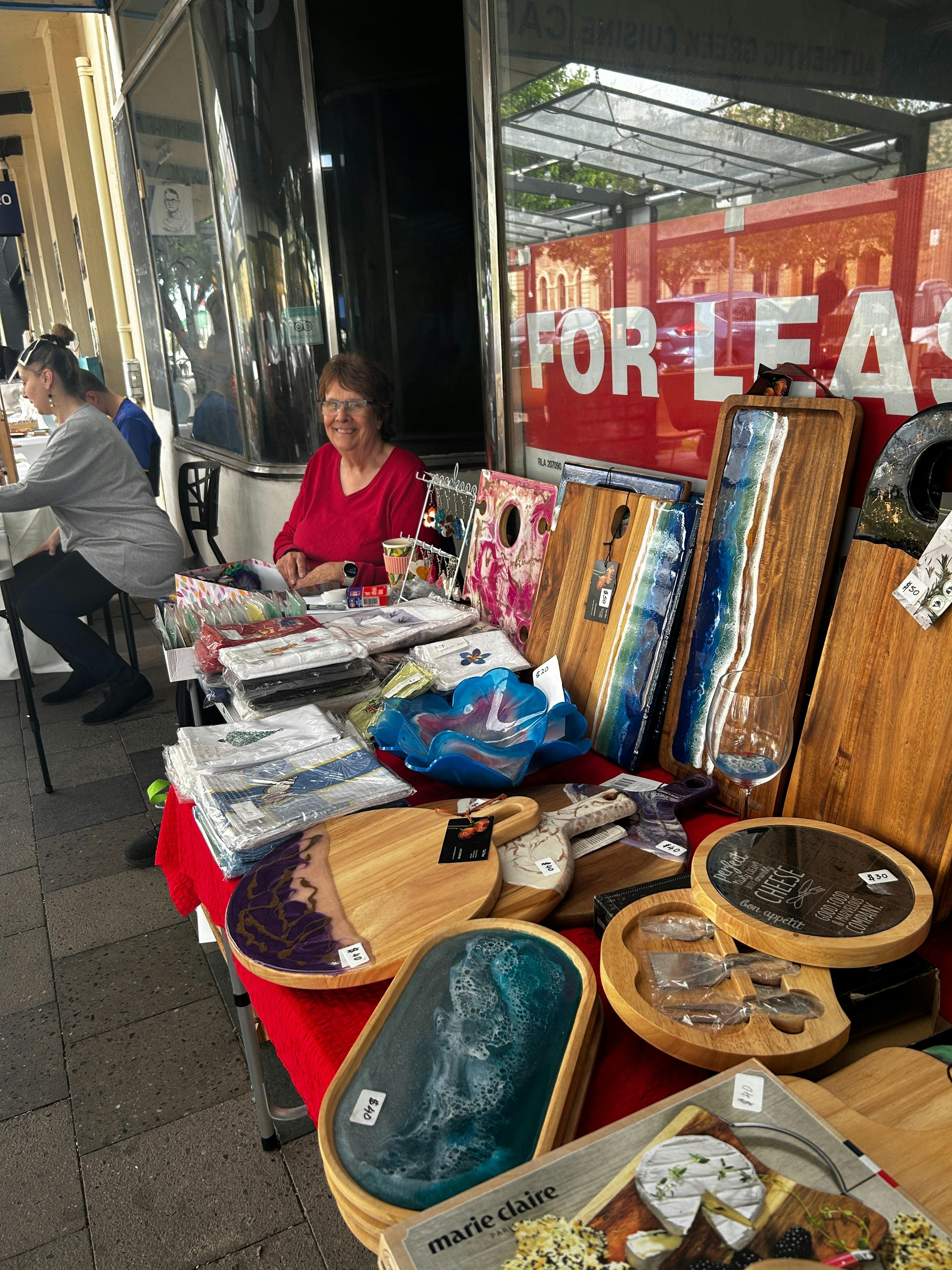 Local artisan showcasing handcrafted resin boards and homewares at Meandering Markets.