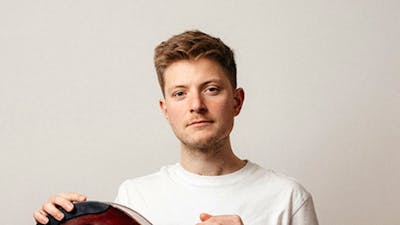 Photo of a man sitting holding a jazz guitar
