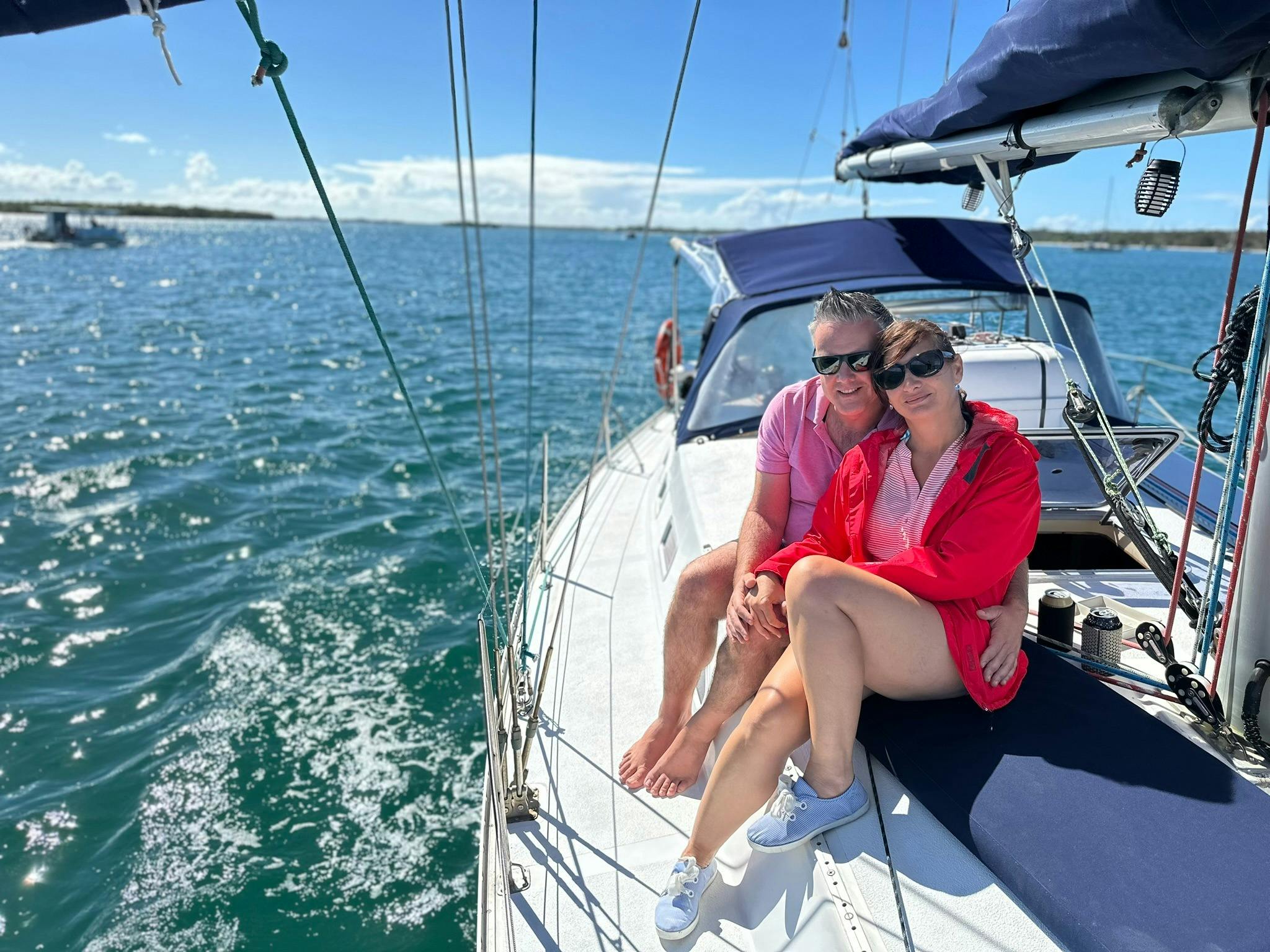 Lady in red and man in pink sitting on the deck of Sun Sailing's yacht during a sunset shared cruise Lady in red and man in pink sitting on the deck of Sun Sailing's yacht during a sunset shared cruise