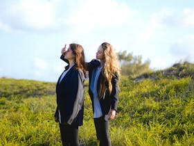 Photograph of two girls in school uniform, in a grassy field.
