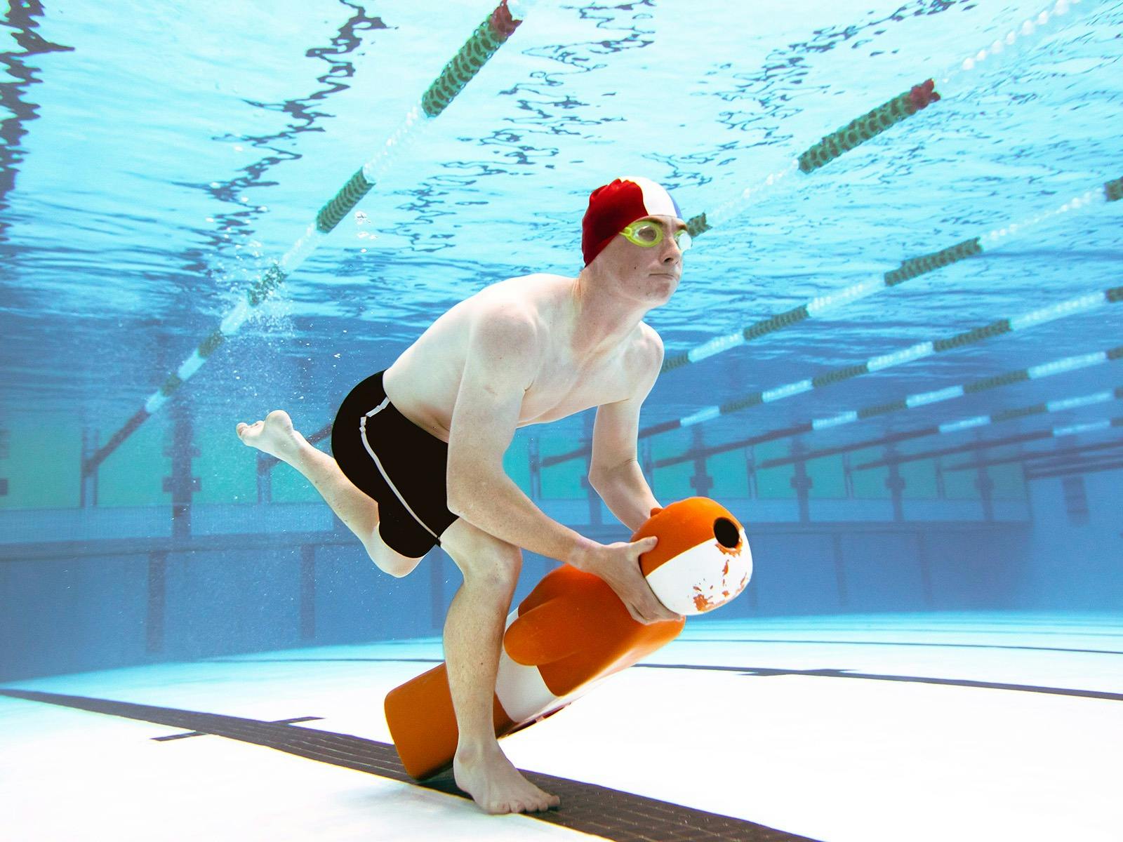 A pool rescue competitor lifting a rescue manikin off the bottom of a pool