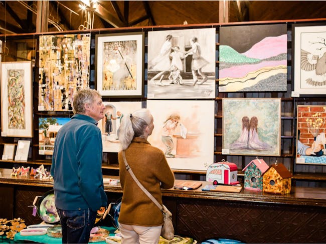 people looking at paintings hanging on the wall