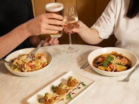Diners toasting drinks while enjoying meals at Risdon Hotel.