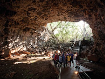 Tour group and guide in tube with opening in the background. Tour group and guide in tube with opening in the background.