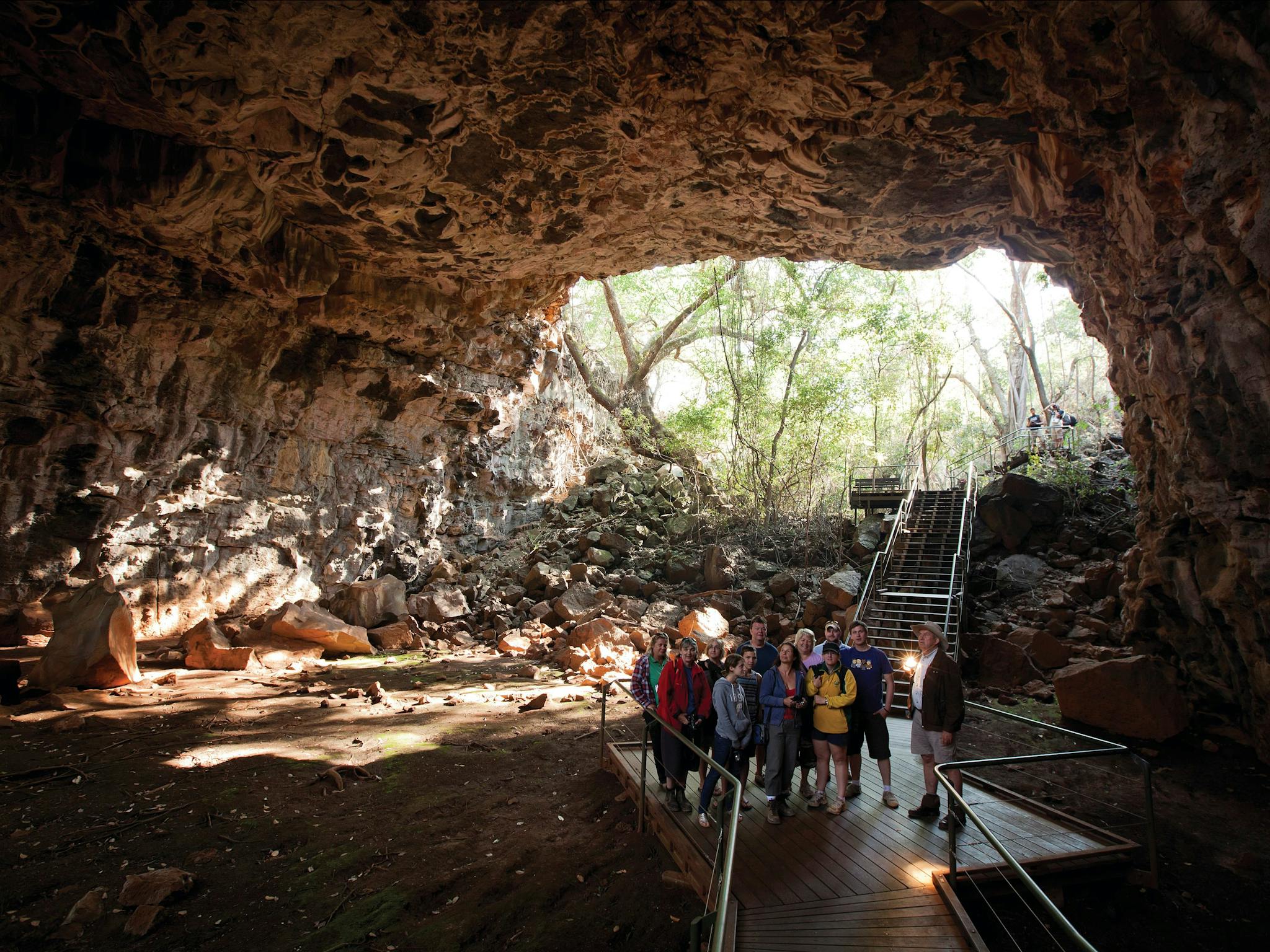 Tour group and guide in tube with opening in the background. Tour group and guide in tube with opening in the background.