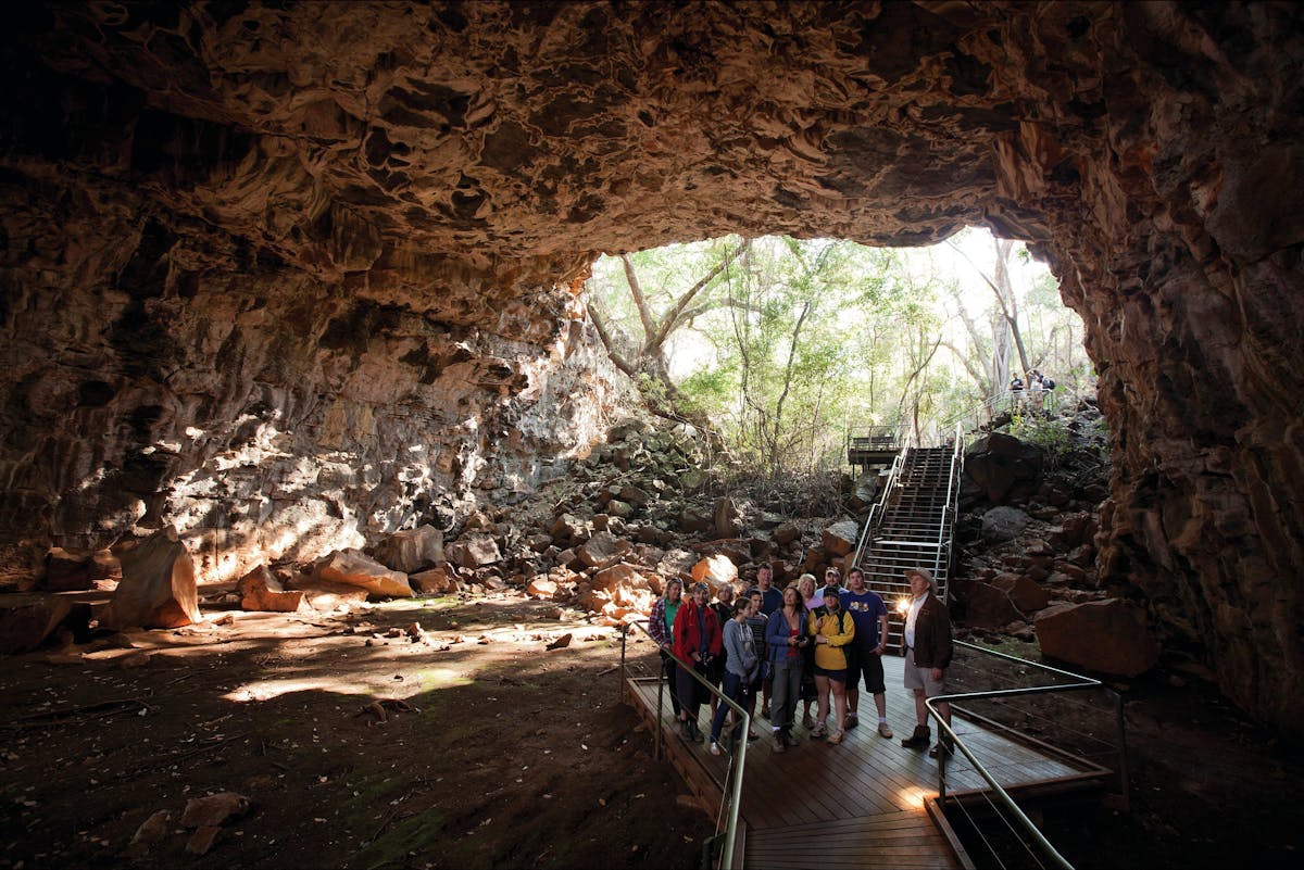 Tour group and guide in tube with opening in the background.