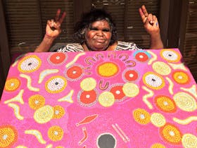 Joyce tjalyiri with her painting about seven sisters at Walkatjara Art gallery Uluru kata tjuta