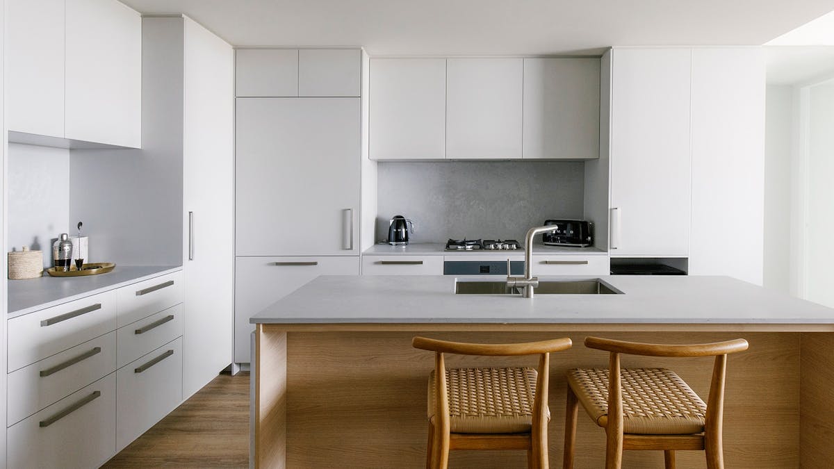 Sleek Kirra Point kitchen with stone island bench, modern appliances, and timber bar stools.