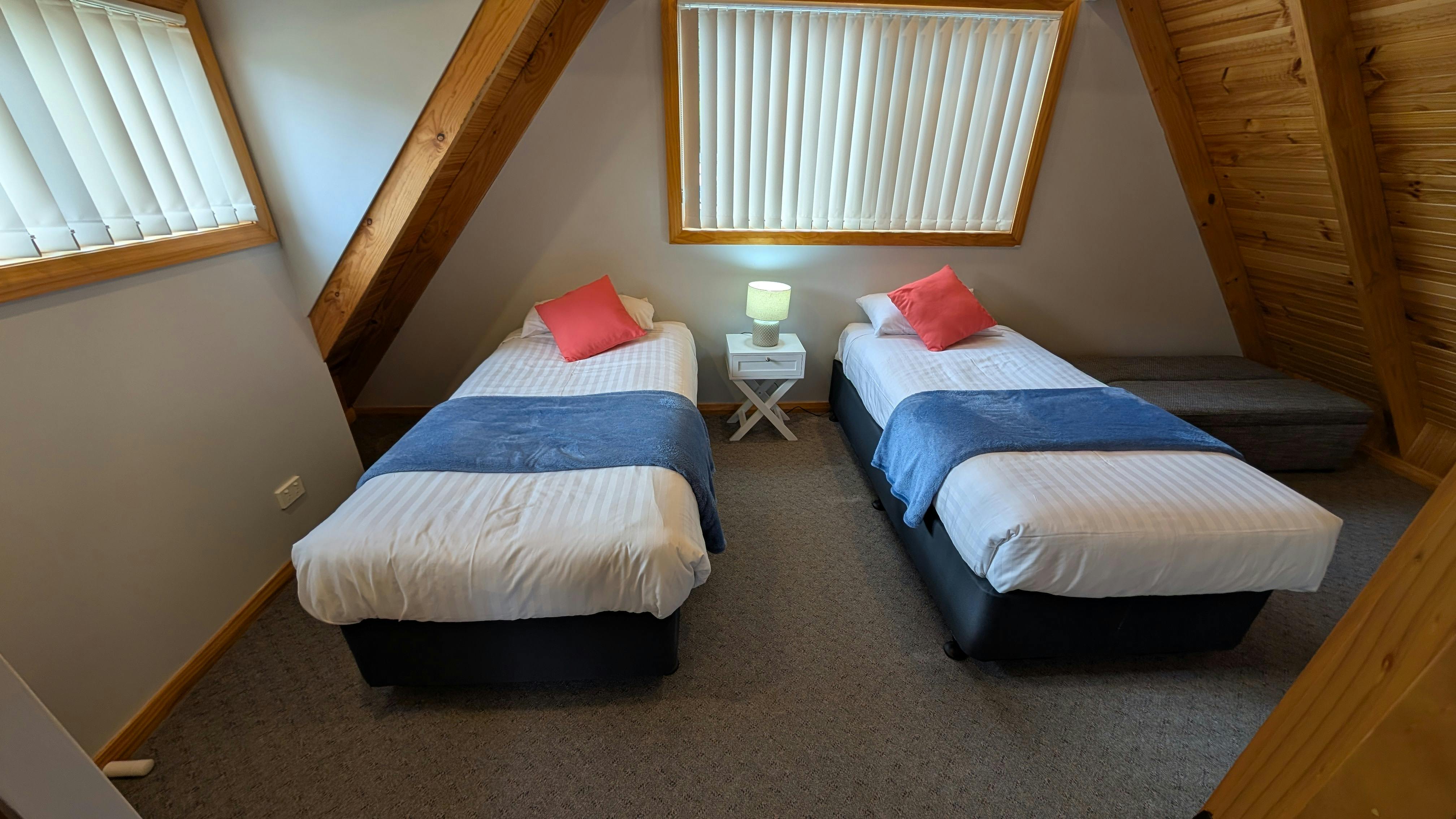 Twin bedroom with two beds, blue throws, timber features and soft lighting.