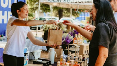 An image of a stallholder handing over a paper bag to a customer