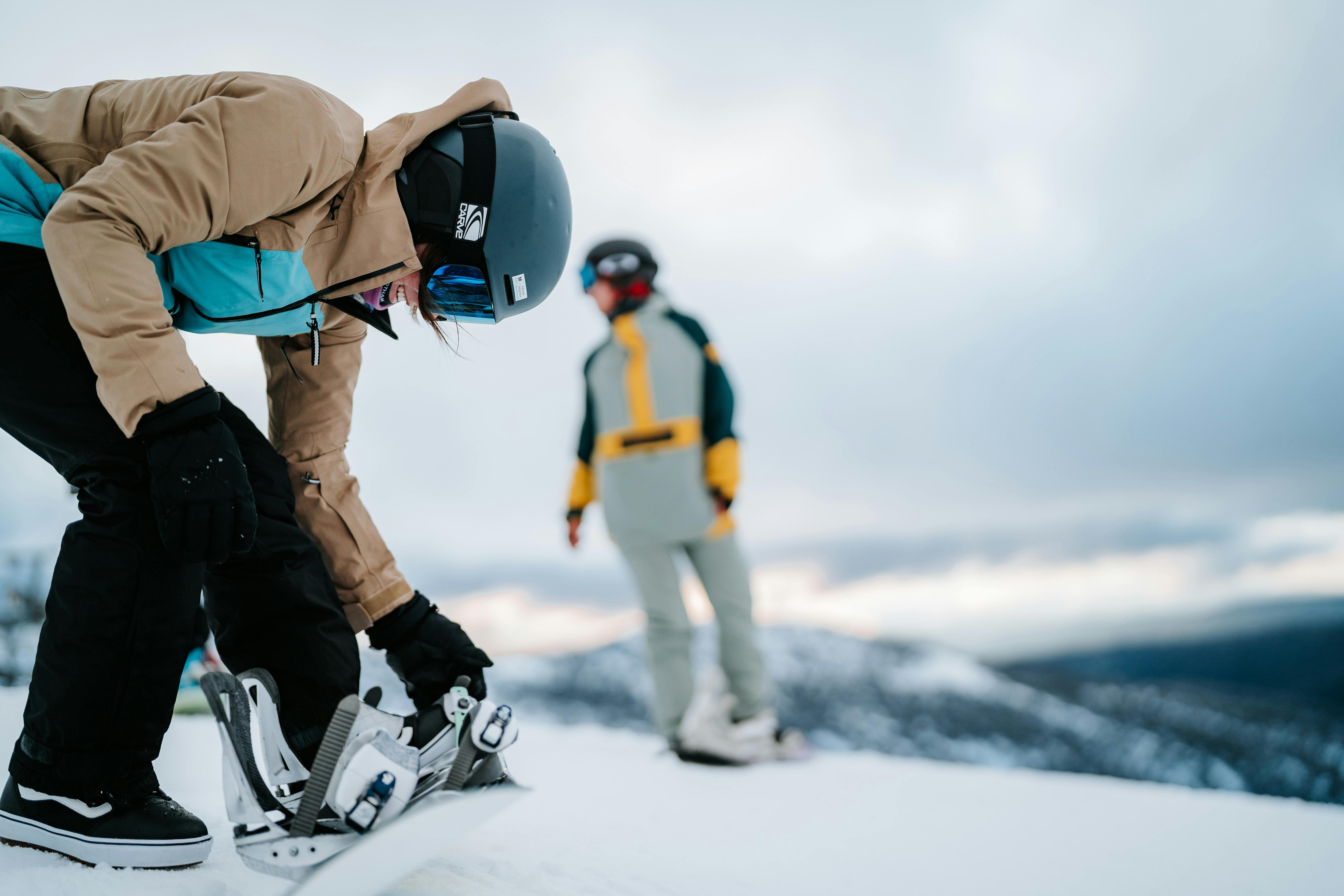Snowboarder strapping boots in against a snowy vita
